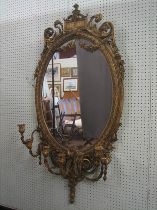 A 19th Century oval plate wall mirror contained in a decorative gilt frame with 6 candle sconces to the base 45" overall