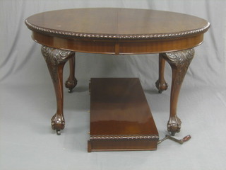An Edwardian Chippendale style mahogany oval extending dining table with gadrooned borders and 1 extra leaf, raised on carved cabriole ball and claw supports 53"