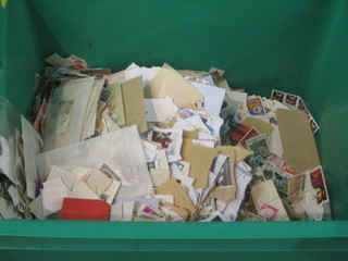 A green plastic crate containing a collection of various stamps