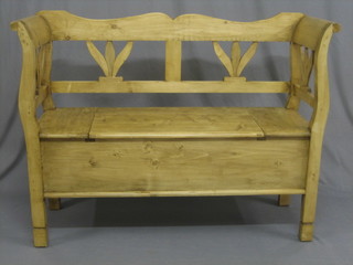 A Continental stripped pine settle with pierced back, the seat with hinged lid 48"