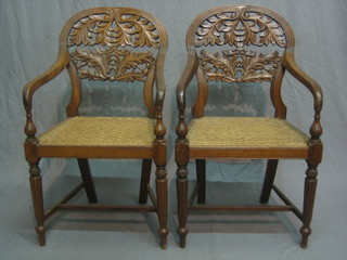 A pair of Eastern carved and pierced hardwood open arm chairs with woven seats, raised on turned supports with H framed stretcher