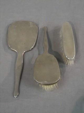A silver backed 3 piece dressing table set comprising hand mirror, clothes brush and hair brush, London 1979