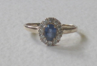 A yellow gold cluster dress ring set a sapphire surrounded by diamonds