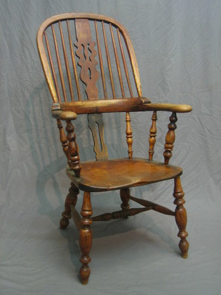 An 18th/19th Century elm Windsor chair with pierced slat back and broad arms, raised on turned supports