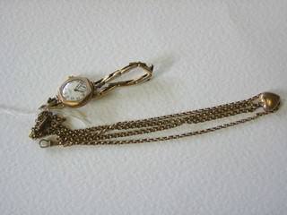 A lady's gold cased wristwatch by J W Benson together with a gilt metal belcher link chain hung a heart shaped locket and a gilt metal belcher chain