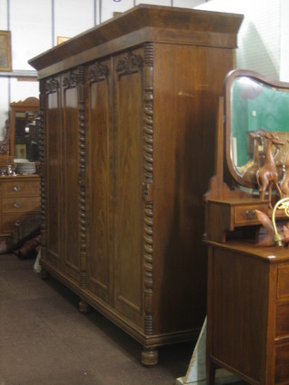 A William IV Chanel Islands mahogany double wardrobe with moulded cornice, enclosed by 4 panelled doors and with spiral turned decoration, raised on bun feet 96"