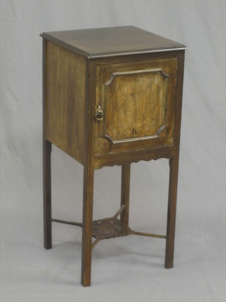 An Edwardian style mahogany bedside cabinet enclosed by a panelled door, raised on square tapering supports with X framed stretcher and undertier 13"