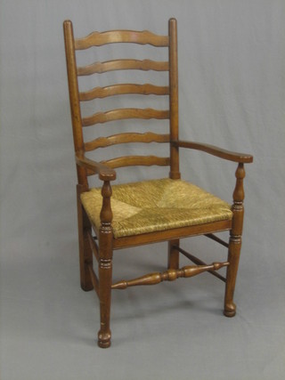 An elm Lancashire ladder back open arm carver chair with rush seat, raised on turned supports