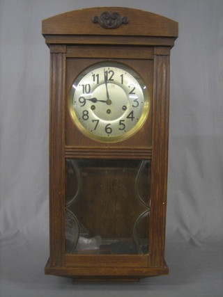A chiming wall clock with silvered dial and Arabic numerals, contained in an oak case