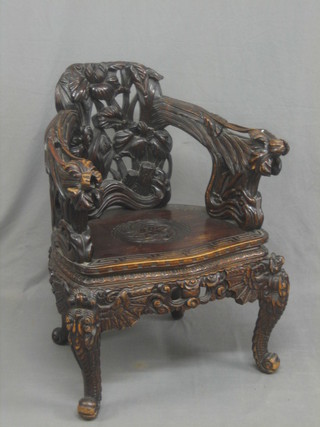 A 19th Century carved and pierced Eastern hardwood tub back chair raised on stylised cabriole supports