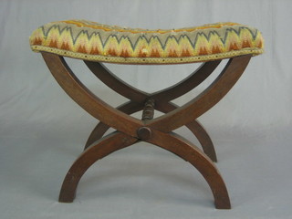 A 19th Century mahogany saddle shaped stool, raised on X framed supports 22"