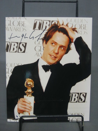 A signed colour photograph of Hugh Grant receiving a Gold Globe, 10" x 8"
