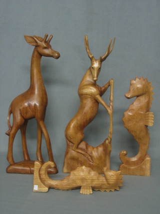 A carved wooden figure of a Stag 17", a carved figure of a giraffe, 2 carved figures of sea horses and a carved figure of a Shark