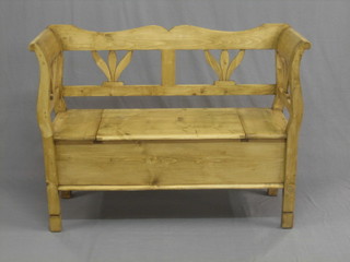 A Continental stripped and polished pine settle with pierced back, and hinged seat lid, 48"