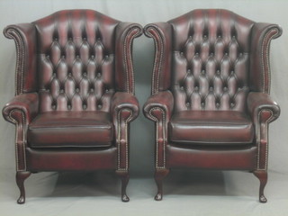 A pair of Georgian style mahogany framed armchairs, upholstered in red leather buttoned material, raised on cabriole supports (as new)