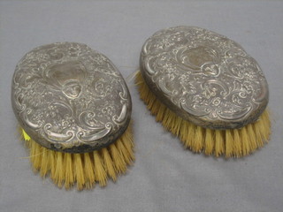 A pair of silver backed military hair brushes with embossed decoration