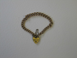 A gold curb link bracelet with heart shaped padlock