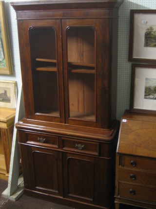 A Victorian mahogany bookcase on cabinet, the upper section with moulded cornice, the interior fitted adjustable shelves enclosed by D shaped panelled glazed door, the base fitted 2 long drawers above a double cupboard, raised on a platform base 41"