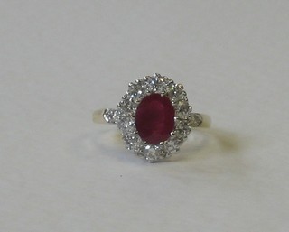 An 18ct yellow gold dress set an oval cut ruby surrounded by diamonds, approx 0.90/1.35ct