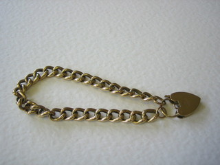 A 9ct gold curb link bracelet with heart shaped padlock