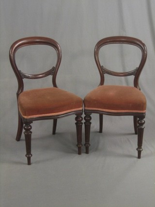 A pair of Victorian mahogany balloon back dining chairs with upholstered seats, raised on turned supports