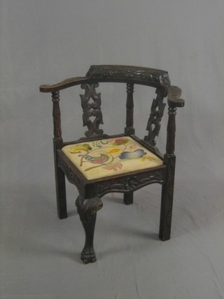 A Victorian carved oak splat back corner chair, raised on cabriole supports