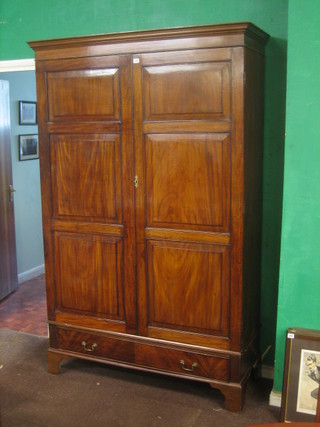 A Channel Islands mahogany wardrobe with moulded cornice enclosed by a panelled door, the base fitted 1 long drawer, raised on bracket feet 52"