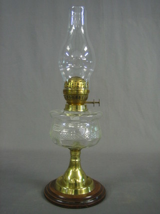 A cut glass oil lamp reservoir raised on a brass column with wooden socle base