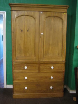 A 19th Century polished pine linen press, the upper section with moulded cornice, the interior fitted 3 shelves enclosed by arch shaped panelled doors, the base fitted 2 short and 2 long drawers, raised on a platform base 48"