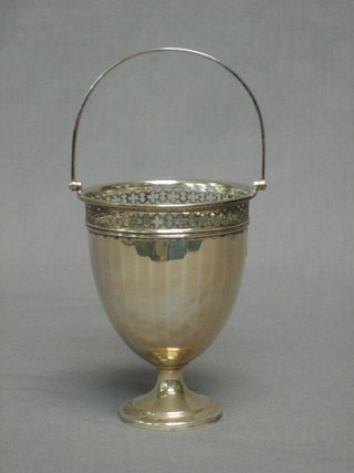 A circular silver Georgian style sugar bowl with pierced decoration and swing handle, raised on a spreading foot Birmingham 1935 with Jubilee hallmark 3 ozs