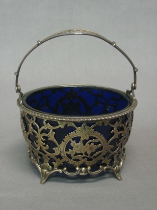 An Edwardian circular pierced silver sugar bowl with swing handle, raised on 4 panel supports, London 1905 complete with blue glass liner, 3 ozs
