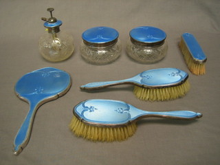 A 7 piece matched blue enamel and silver dressing table set comprising handmirror, pair of hair brushes, clothes brush, pair of cut glass dressing table jars with lids and perfume atomiser (slight chip to enamel on atomiser) London 1930, 32 and 35