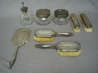 An 8 piece Art Deco silver backed matched dressing table set comprising hand mirror (chip to glass), pair of hair brushes, pair of clothes brushes, 2 cut glass dressing table jars with silver lids, globular shaped perfume atomiser with silver and plated mount, London 1932, 33 and 48