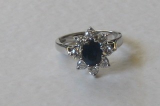 An 18ct white gold dress ring set a large oval sapphire surrounded by diamonds