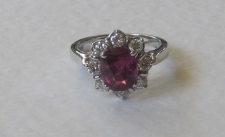 An 18ct white gold dress ring set an oval ruby surrounded by diamonds