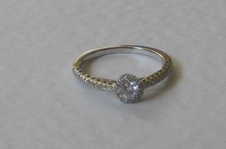 An 18ct white gold dress ring set a solitaire diamond and with numerous diamonds to the shoulders