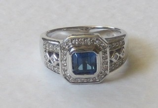 A 14ct white gold dress ring set a square cut sapphire supported by diamonds
