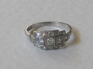 A platinum Art Deco style dress ring set 3 diamonds to the centre supported by 6 diamonds and with baguette cut diamonds to the shoulders