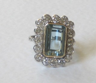 An 18ct gold dress ring set a large rectangular cut aquamarine surrounded by 16 diamonds, approx 2.5/7.40ct