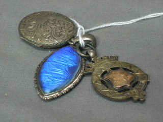 A silver watch chain medallion, a silver locket and a silver butterfly pendant