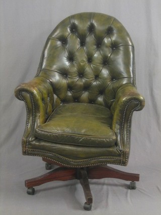 A revolving office chair upholstered in green buttoned leather