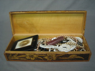 A rectangular carved wooden box containing various items of costume jewellery