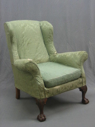 A Georgian style mahogany winged armchair upholstered in green material, raised on cabriole ball and claw supports