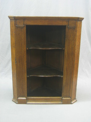 A 19th Century oak hanging corner cabinet with moulded cornice fitted shelves and having column decoration to the side 31"