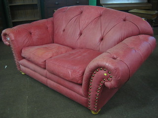 A Chesterfield style 2 seat sofa upholstered in red buttoned back leather 70"