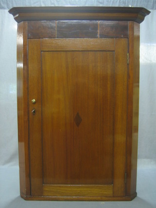 A mahogany hanging corner cabinet with moulded cornice, the interior fitted adjustable shelves enclosed by a panelled door 29"