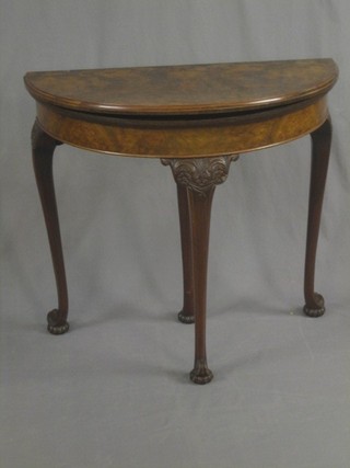 A 1930's Georgian style figured walnut demi-lune carved table, raised on carved cabriole supports 32"