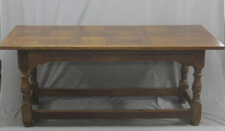An oak refectory dining table, with panelled top, raised on turned and block supports 72"