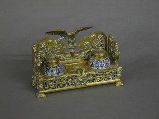 A 19th Century pierced brass inkwell surmounted by a figure of an eagle with wings outstretched, fitted a stamp box to the centre (hinge f) and having 2 blue porcelain inkwells 9 1/2" 