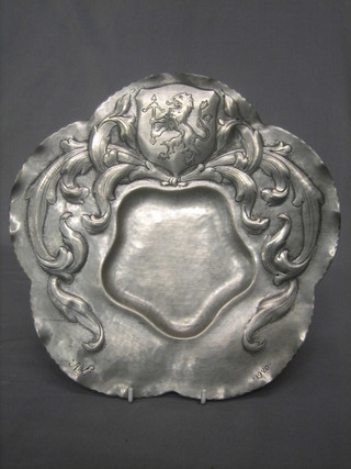 An embossed pewter dish with armorial decoration, marked A & L 1920 11"